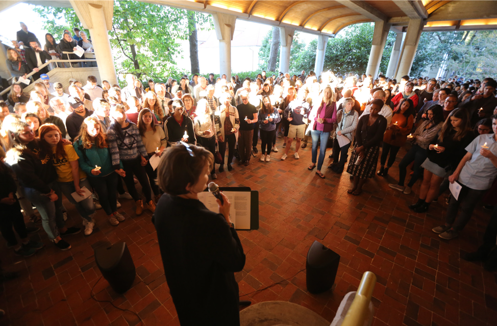 A chaplain speaking to a large group of students during a vigil