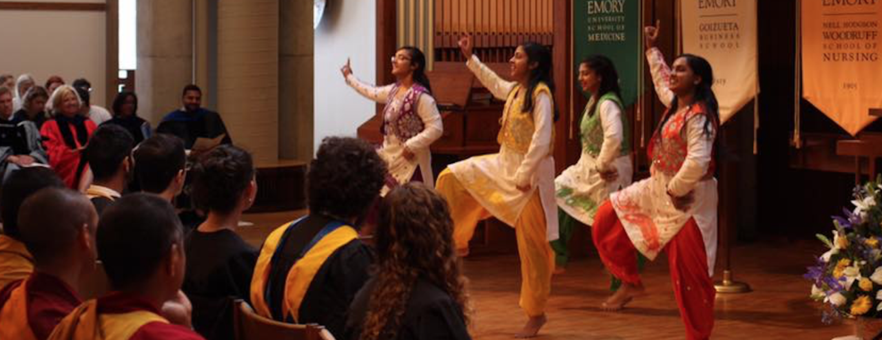 Four women in colorful attire performing a dance during a spiritual life program