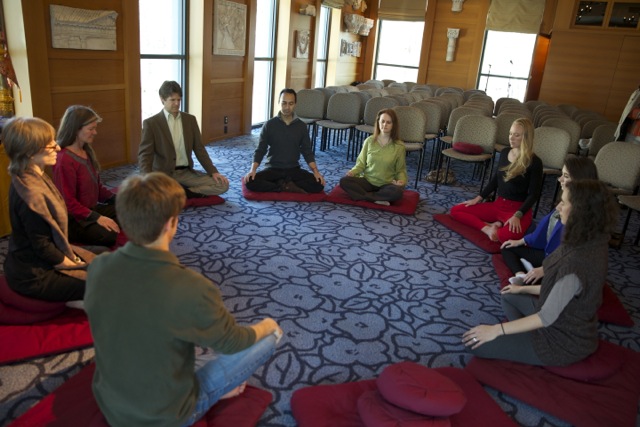 Students sitting in a circle on the floor in meditative pose